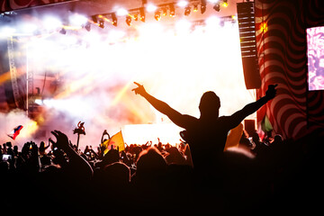 Silhouette of man with raised hands on music concert