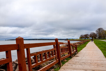 Redwood painted fence, lines wooden walkway winding around  ocean cove in Charlottetown, Canada.