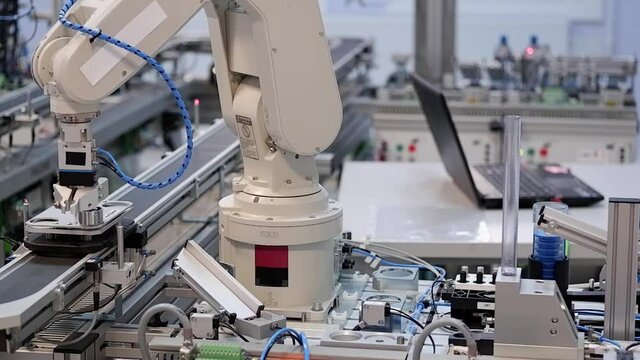 Close-up of robot arm pick product from automated car and place to station to be assembly. Industry 4.0 smart factory concept; robot arm assembles the product. Selective focus.