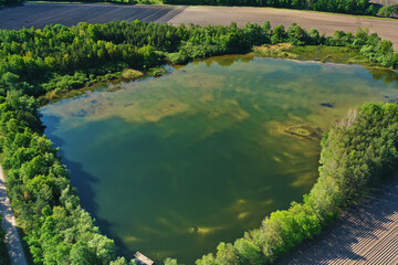 Aerial view of an almost rectangular shallow pond, through whose clear surface the sandy bottom shimmers