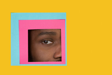 Calm. Eye of emotional african-american man peeks throught square in yellow background. Trendy geometrical style, copyspace. Vibrant colors. Sales, proposal, finance and business concept. Framing.