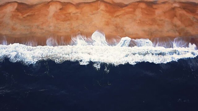 Flying over a sandy beach. Waves break on a sandy beach on the Atlantic coast, aerial View. Nazare, Portugal.