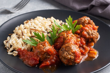 Beef meatballs and brown rice on a plate. Ready made portioned dish meat with garnish.
