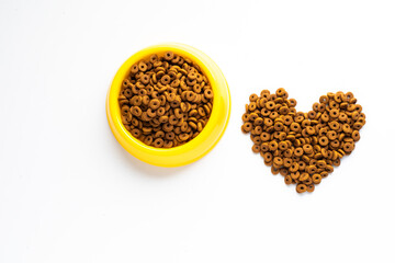 Dried dog food with a shape of heart on white background. Top view Brown grain pet food banner background with copy space of text design.