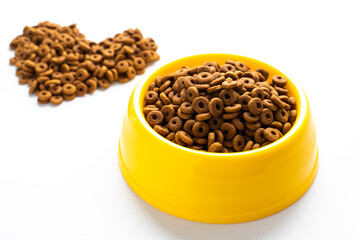 Yellow plastic bowl full with dry dog food isolated on white background. Top view grain pet food with copy space of text design. Above or Top view. food texture banner..
