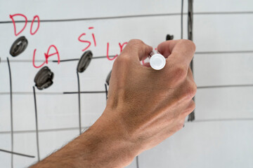 Adult hobby course,writing music notes with red pencil on whiteboard, closeup