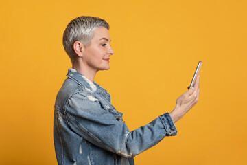 Biometric identification. Modern smiling middle-aged woman with smartphone scanning face in app