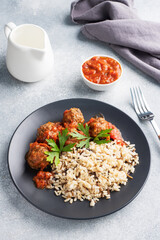 Beef meatballs and brown rice on a plate. Ready made portioned dish meat with garnish. Copy space.