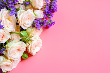 a bouquet of cream roses and bright purple flowers in full bloom on a pink background with space for text. greeting card