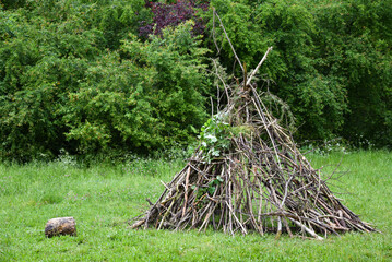 Hut of branches in woods. Playground at nature, childhood natural lifestyle, simple joy, survival skills concepts. © Elena Dijour