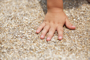 Baby small hand touching brown sand in Thailand 