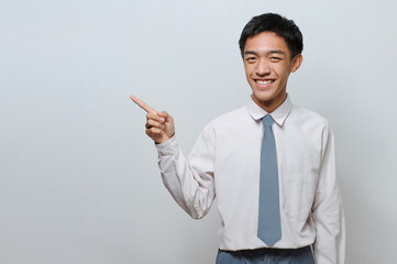 Indonesian Senior Student wearing uniform pointing at copy space or blank space
