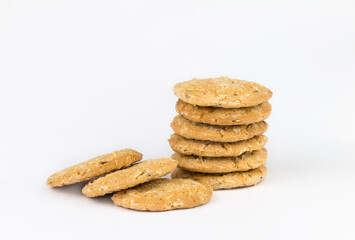 Cereal cookies are stacked on top of multiple pieces and have three pieces overlapped on each side.Cookies are brown and the image has blank space on the side of the object and has a white background.