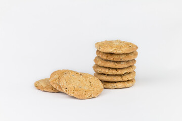 Cereal cookies are stacked on top of multiple pieces and have three pieces overlapped on each side.Cookies are brown and the image has blank space on the side of the object and has a white background.