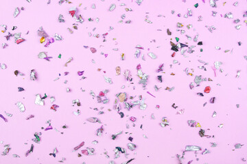 Multicolored confetti on pink background. Flat lay, top view.