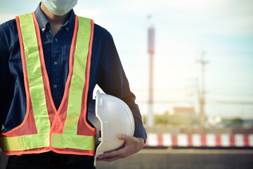 Asian man holding safety helmet on factory background,Engineer holding white safety helmet
