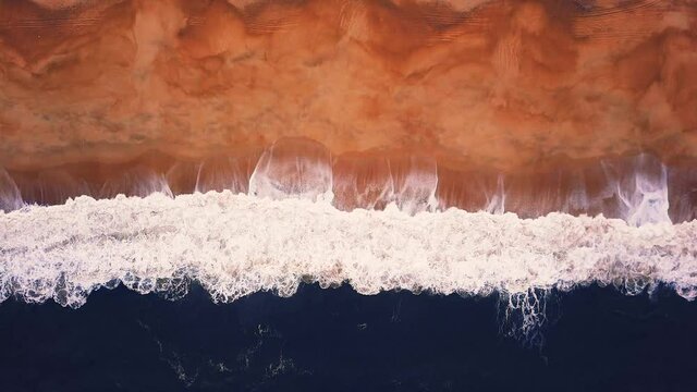 Flying over a sandy beach. Waves break on a sandy beach on the Atlantic coast, aerial View. Nazare, Portugal.