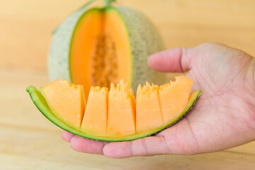 The man use knife split the orange melon on wood plate