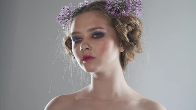 Portrait of a pretty girl on a light background, studio shooting on the theme of spring, girl with flowers in her hair.