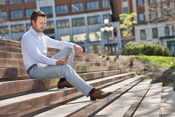 Obraz premium Portrait of an handsome man on the urban background holding phone