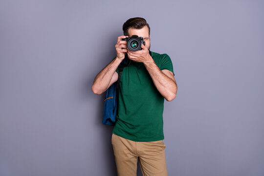 Portrait of concentrated guy enjoy travel weekend use professional camera shooting picture wear green pants isolated over gray color background