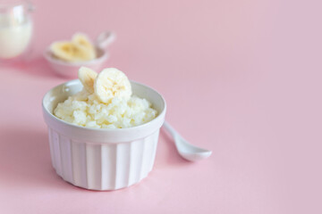 Milk rice porridge with banana in a white mask on a pink background, can be used for article, banner and infographic