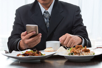 businessman checking the news from mobile phone while eating breakfast near window