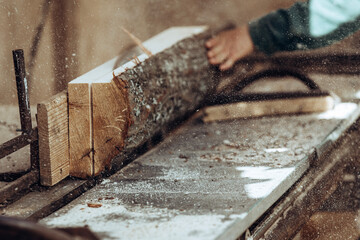 Carpenter cuts wooden board on circular saw.
