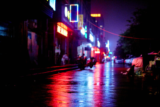 Neon lights at night in Shanghai, China. Shot on a rainy night on the backstreets. Normal life in this busy city. Blues, reds and orange run through this image, with strong coloured reflections