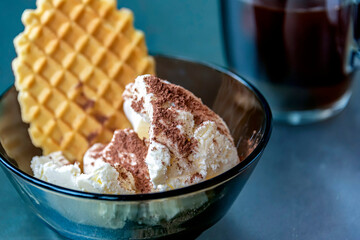 Ice cream with chocolate and waffles in plate on the table.