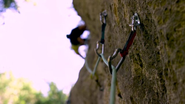 Close-up of rock climbing equipment swinging from rock wall in slow motion