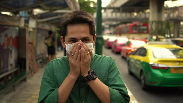 A man wearing mask protective for spreading of disease virus Covid-19 and air smog pollution with PM 2.5 with coughing on street at chatuchak district in  Bangkok city, Thailand.