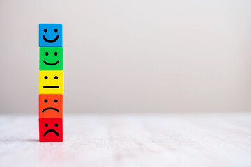 Emotion face symbol on yellow wooden cube blocks. Service rating, ranking, customer review,...