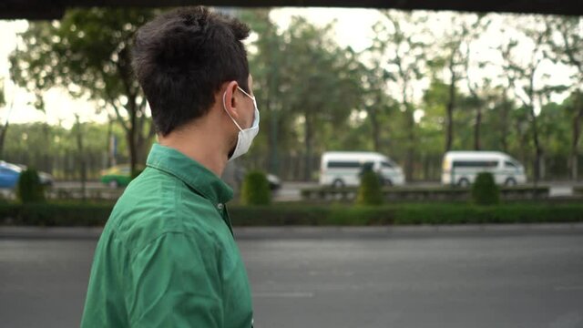 A man wearing mask protective for spreading of disease virus Covid-19 and air smog pollution with PM 2.5 while walking on street at chatuchak district in  Bangkok city, Thailand.