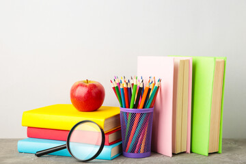 Multi coloured school books and stationery on grey background