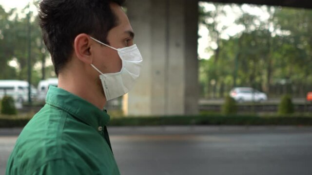 A man wearing mask protective for spreading of disease virus Covid-19 and air smog pollution with PM 2.5 while walking on street at chatuchak district in  Bangkok city, Thailand.