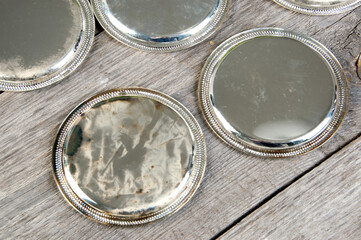 Antique silverplated coasters on wooden background.