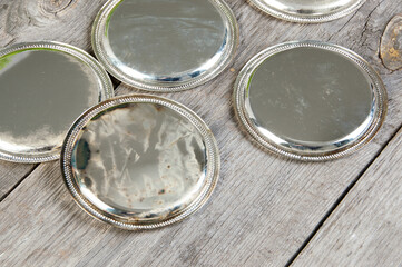 Antique silverplated coasters on wooden background.