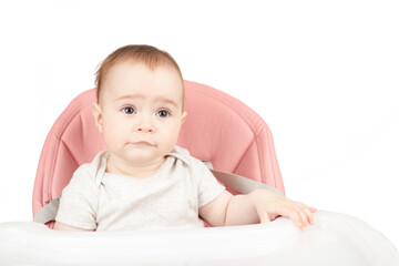 Happy baby girl sitting in a high chair isolated on white background