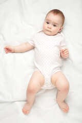 Cute baby girl lying on a white bed.