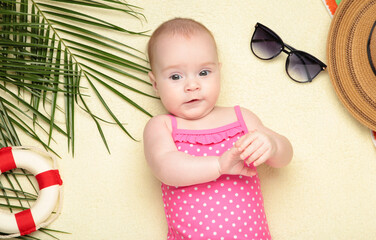 Cute baby girl with beach accessories on light background. Holidays at sea with baby, summer concept