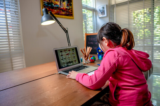 Asian Girl Student Online Learning In Class Study.Online Video Call With Teacher.Child Girl Eating Rice Congee Breakfast With Laptop At Home.New Normal.Covid-19 Coronavirus.Social Distancing.stay Home