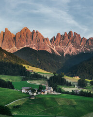 Beautiful village in the Alps. Santa Magdalen on Dolomites Background. Sunset in the mountains in Italy. Red peaks of mountains.