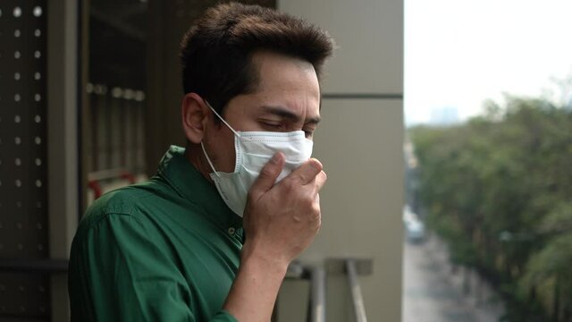 A man wearing mask protective for spreading of disease virus Covid-19 and air smog pollution with PM 2.5 with coughing on skywalk at Chatuchak district in  Bangkok city, Thailand.