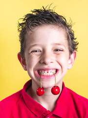 Portrait of a young boy with fresh cherries hanging from his mouth