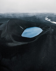 Volcano crater with turquoise lake in Iceland. Aerial view of giant black crater with incredibly blue pool at the top of an ancient volcanic mountain. Travel concept