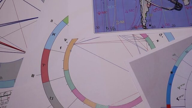 Workplace of a modern astrologer. Astrological charts, tables, diagrams scattered in a mess around the table. Astrological symbols of planets, luminaries, aspects.