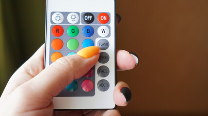 Remote control for change colors in hand on blurred background