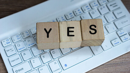 YES word on wood cube block with keyboard background