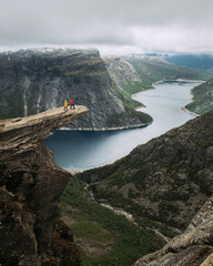 Couple tourist stands on Trolltunga in Norway. Beautiful natural vacation hiking walking travel to nature destinations concept.